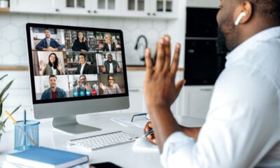 A Black man waving at his colleagues during an online meeting at the front of his PC