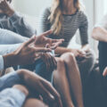 A team in a circle in discussion close up on one person's hands